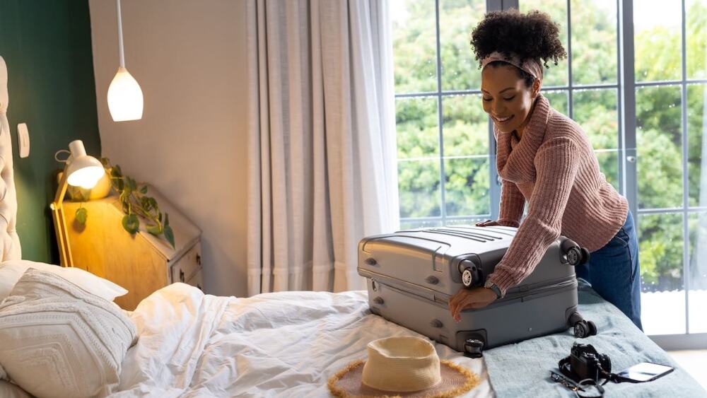 femme défaisant sa valise dans une chambre d’amis