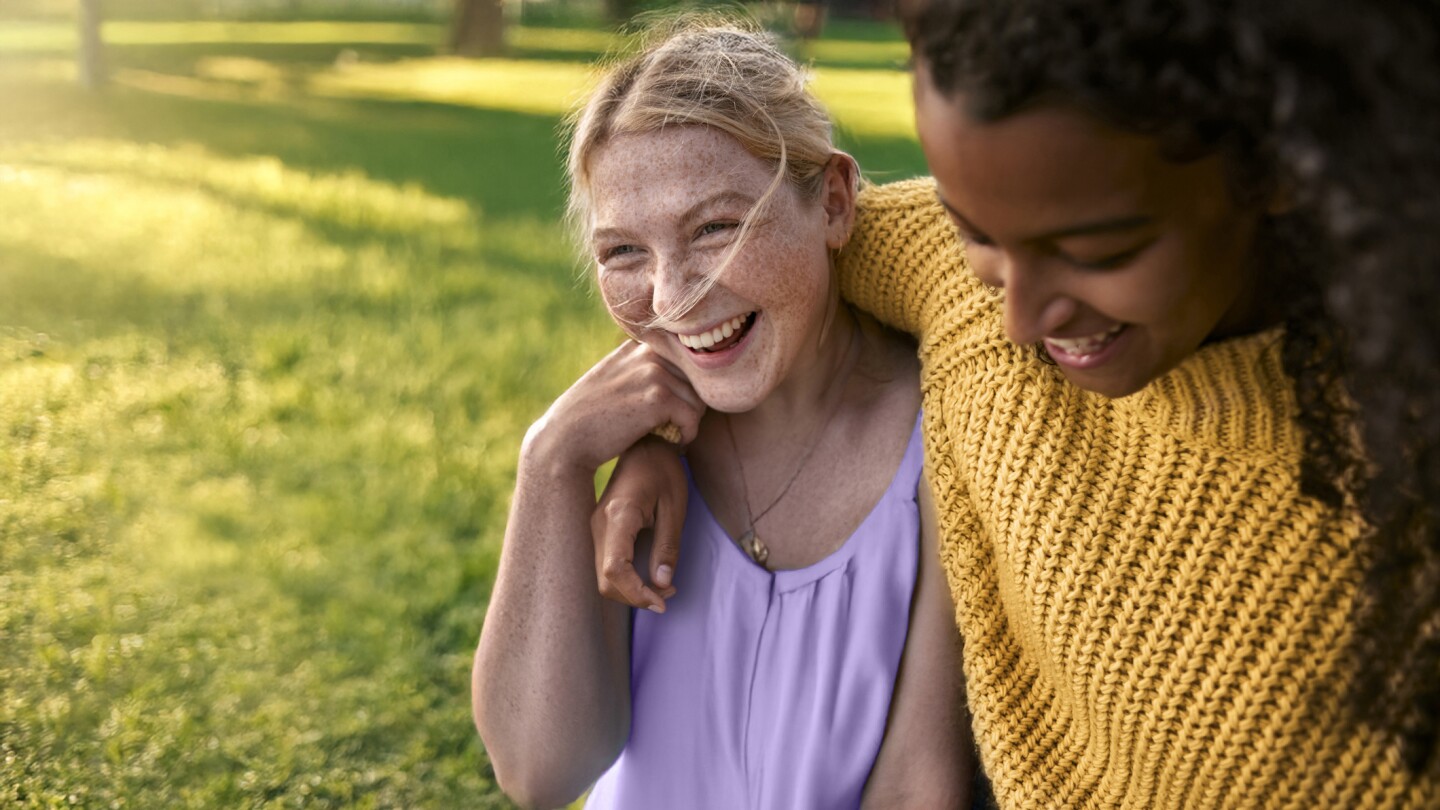 Two happy female friends embracing in a park